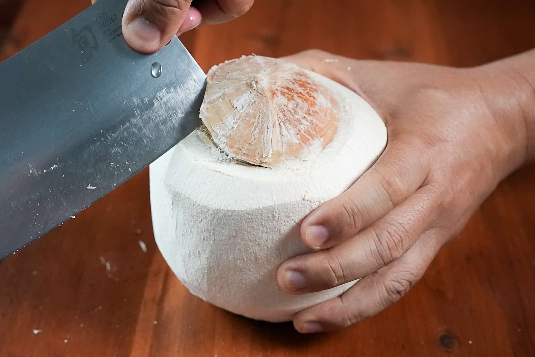 Use knife to pry open top of young coconut