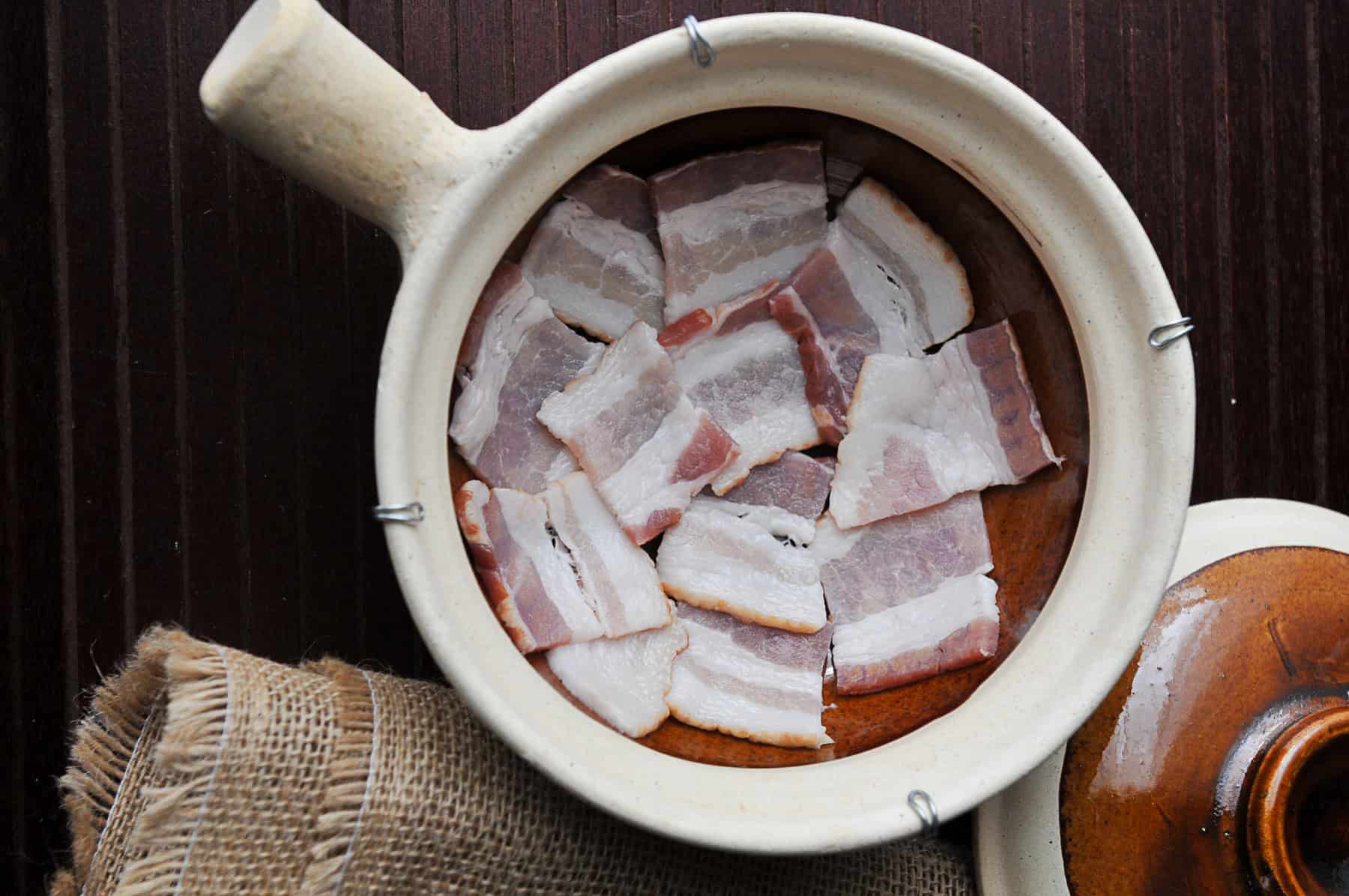 layer bacon on bottom of clay pot