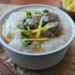 A bowl of jok with meatballs, ginger, and green onion.