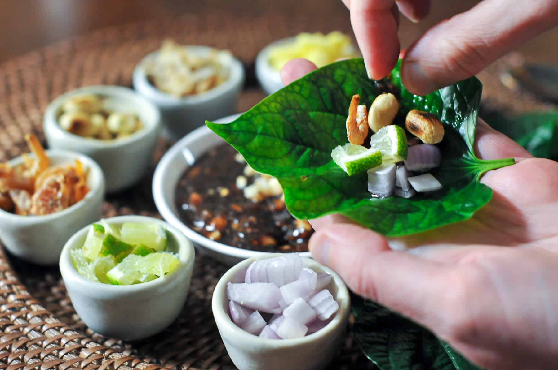 Serve Miang Kham with each ingredient on a plate alongside the sauce and wild pepper leaves. 