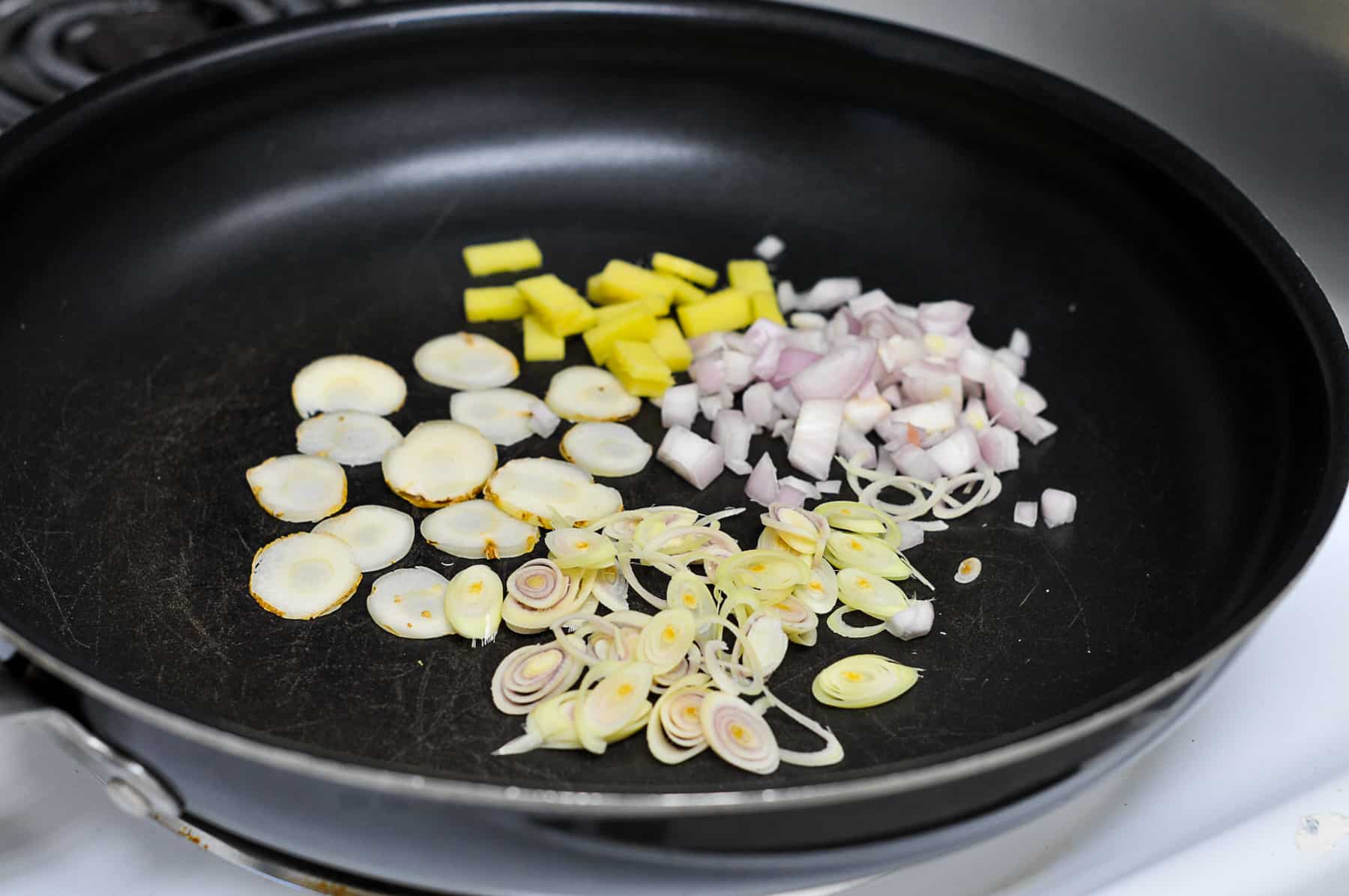 Dry fry the sliced lemongrass, galangal, ginger, and shallots 