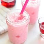 Two glasses of Thai Pink Milk (Nom Yen) with pink straws.
