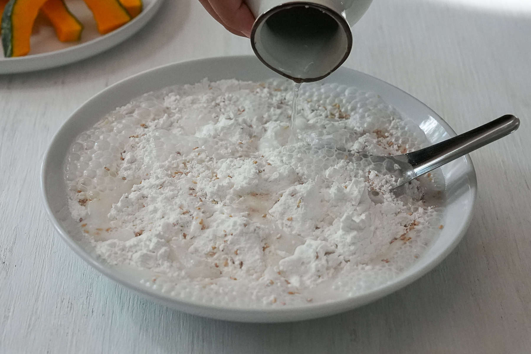 Pouring club soda into the dry ingredients of the batter