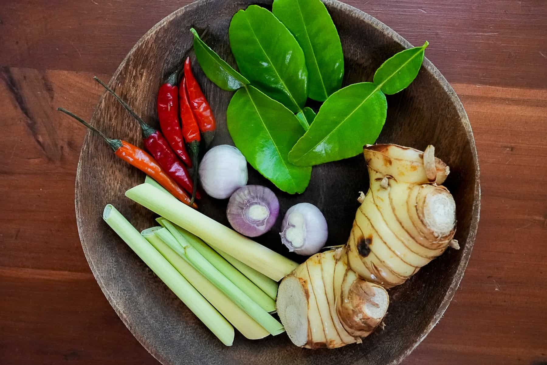 Prepare the kaffir lime leaves, galangal, lemongrass, and shallots for this Tom Kha Gai recipe.