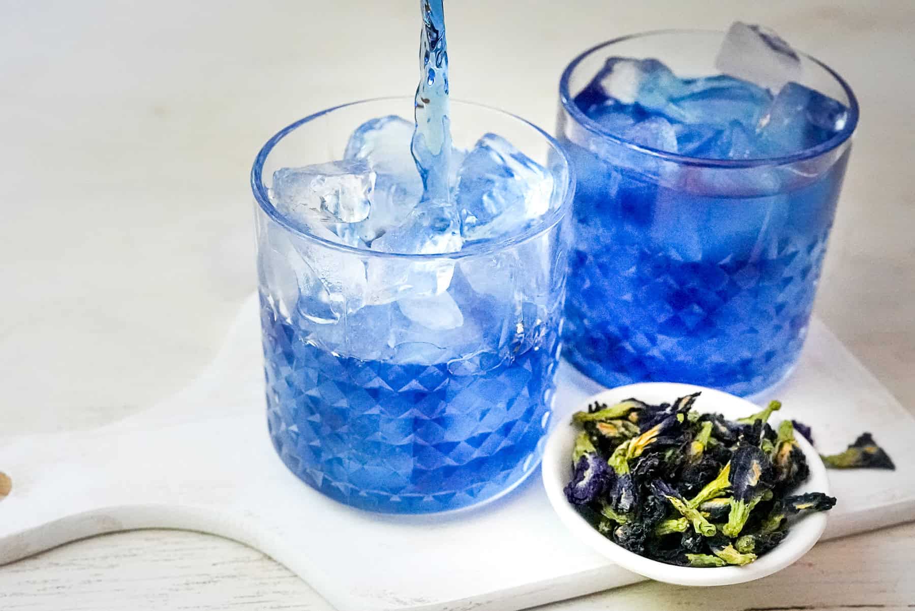 Pour butterfly pea tea into glass with ice