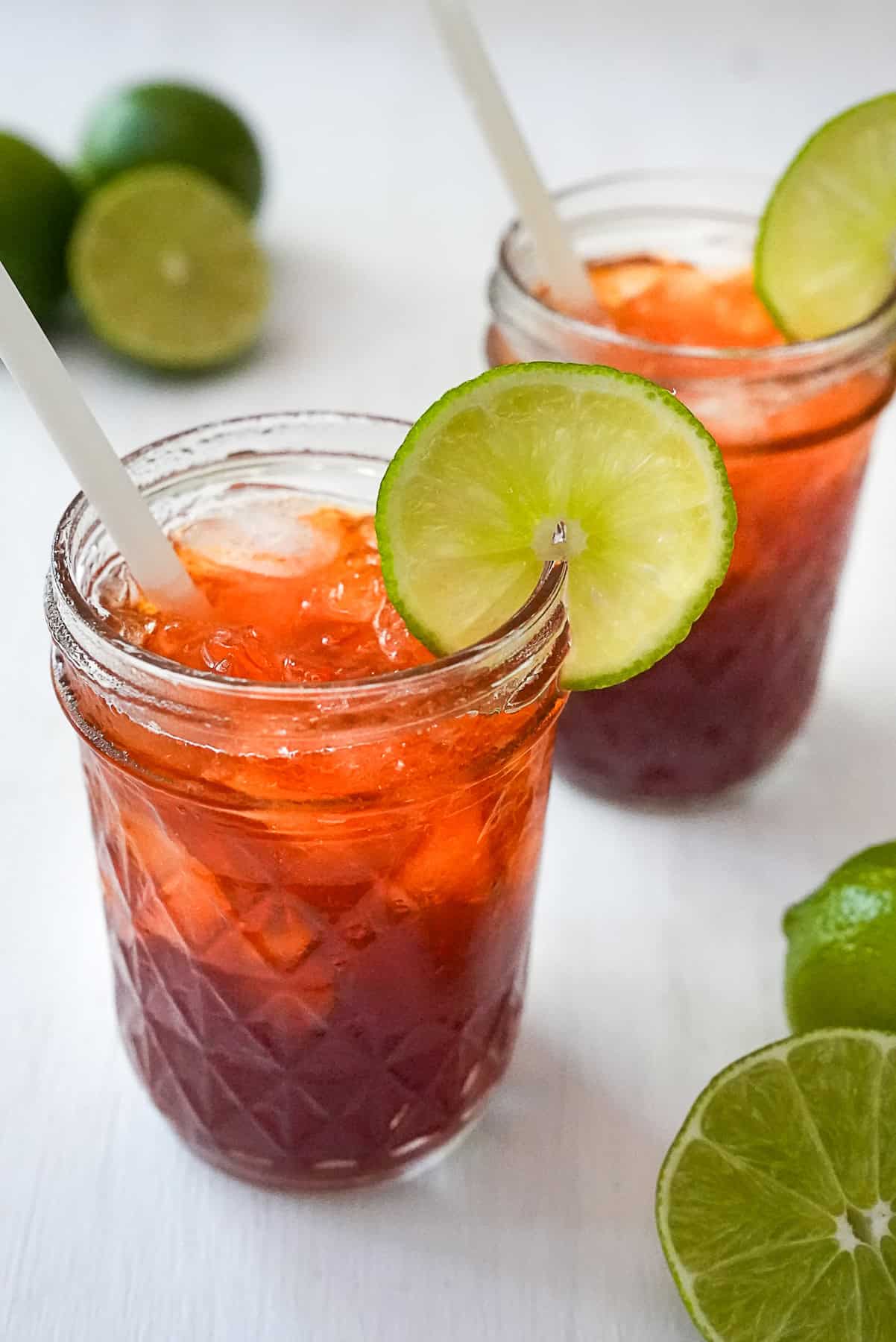 Two glasses of Cha Manao surrounded by limes